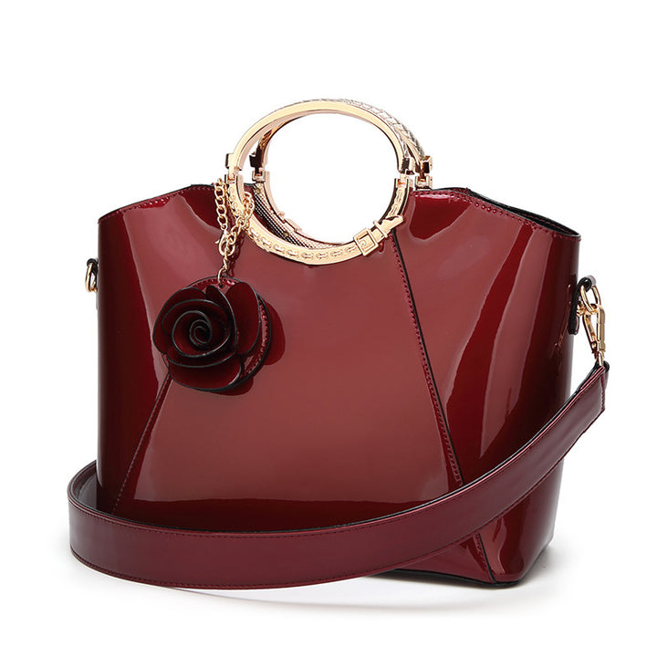 Damen Handtasche mit glänzender Oberfläche und floralem Anhänger Nord Taschen