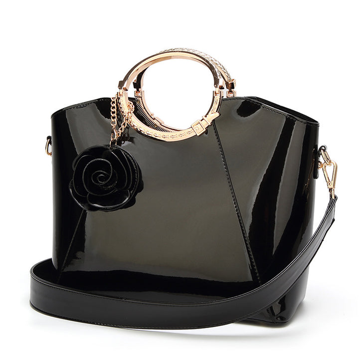 Damen Handtasche mit glänzender Oberfläche und floralem Anhänger Nord Taschen