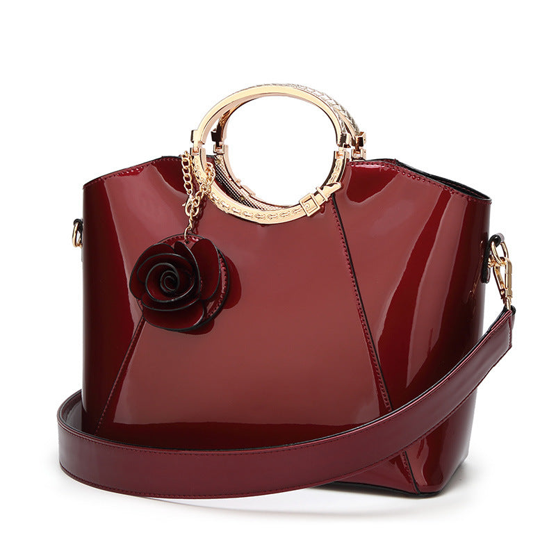 Damen Handtasche mit glänzender Oberfläche und floralem Anhänger Nord Taschen