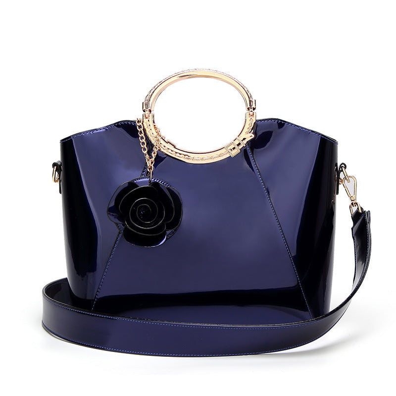 Damen Handtasche mit glänzender Oberfläche und floralem Anhänger Nord Taschen