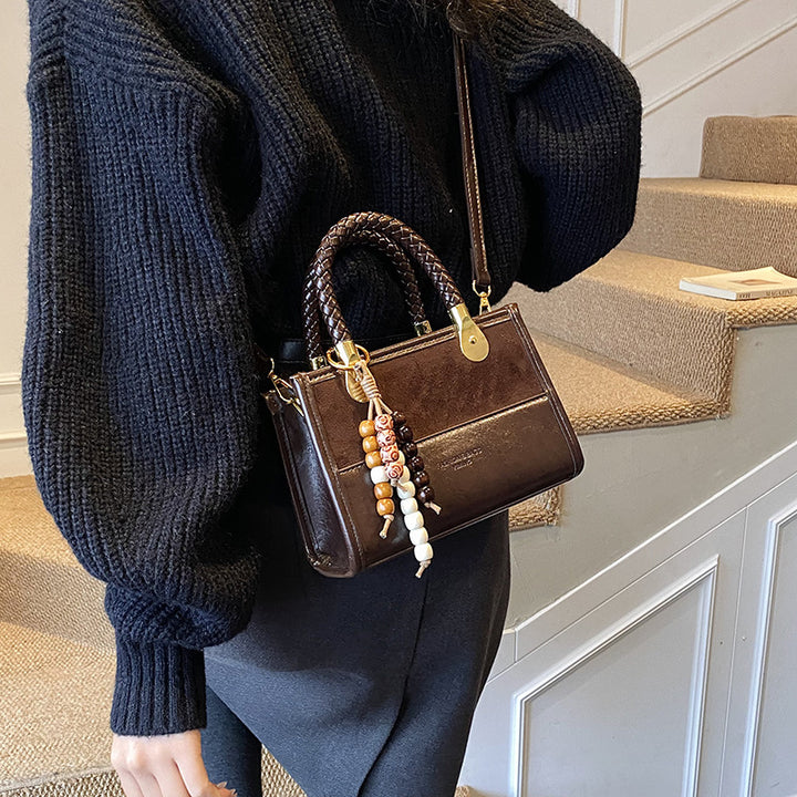 Damen elegante Handtasche mit geflochtenem Henkel und dekorativem Anhänger Nord Taschen