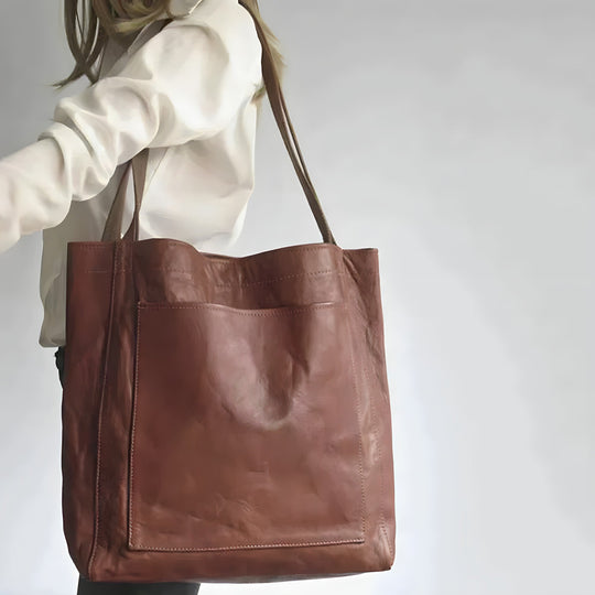 Frau trägt ein weißes Oberteil mit Dunkelbrauner Ledertasche