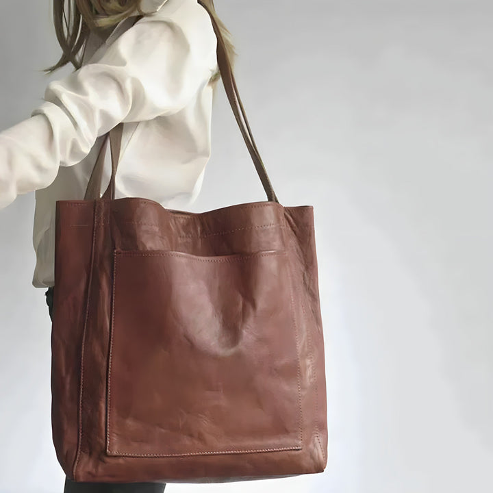 Frau trägt ein weißes Oberteil mit Dunkelbrauner Ledertasche